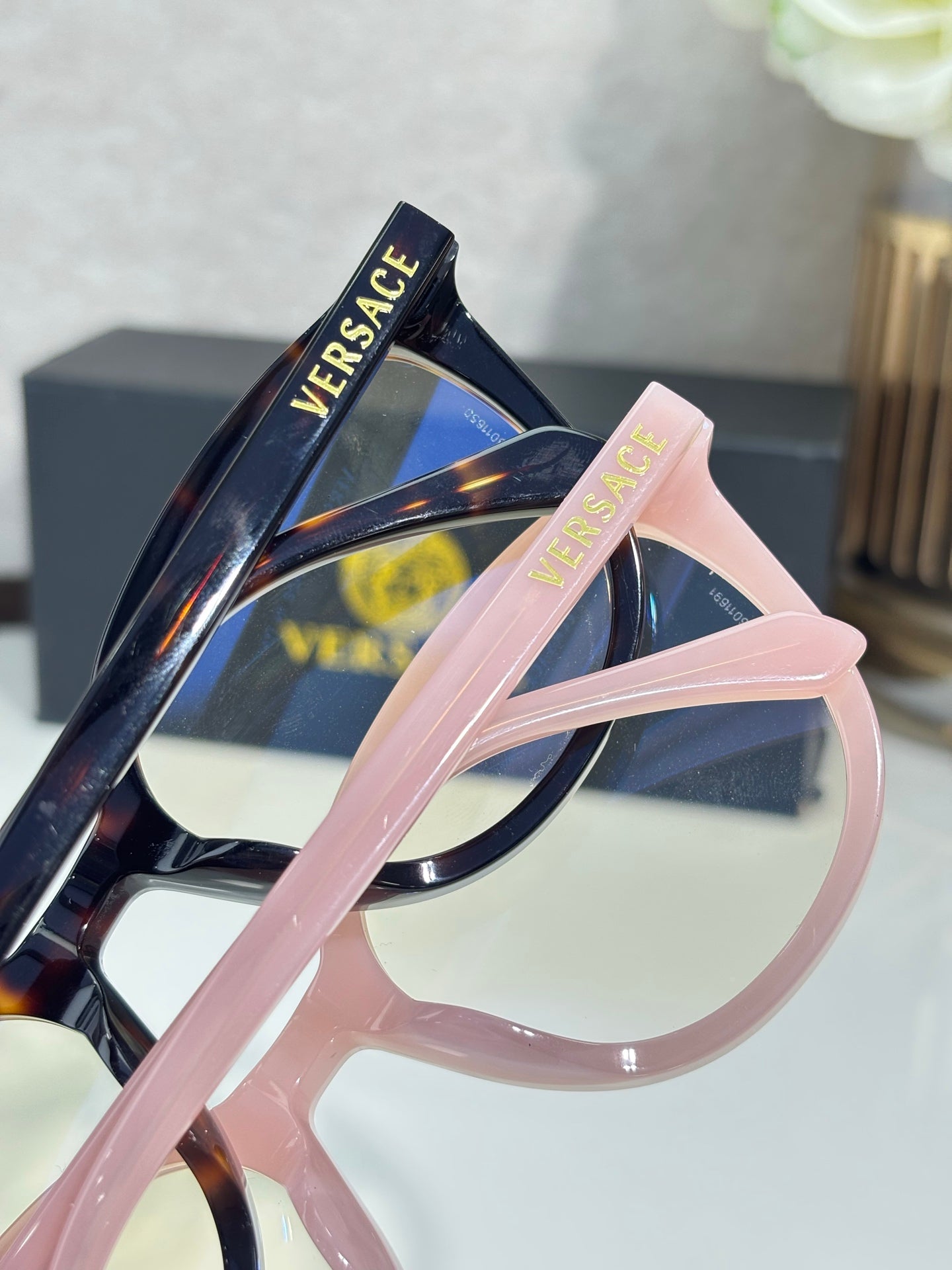Eyeglasses close-up with blush pink frame and logo text on temple