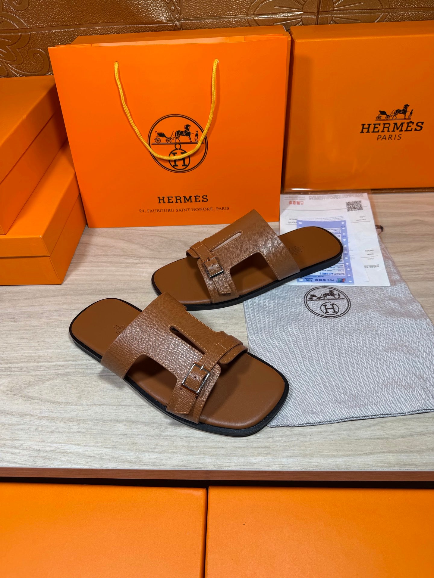 Hermes brown leather sandals with wide straps and metal buckle, two shoes side by side