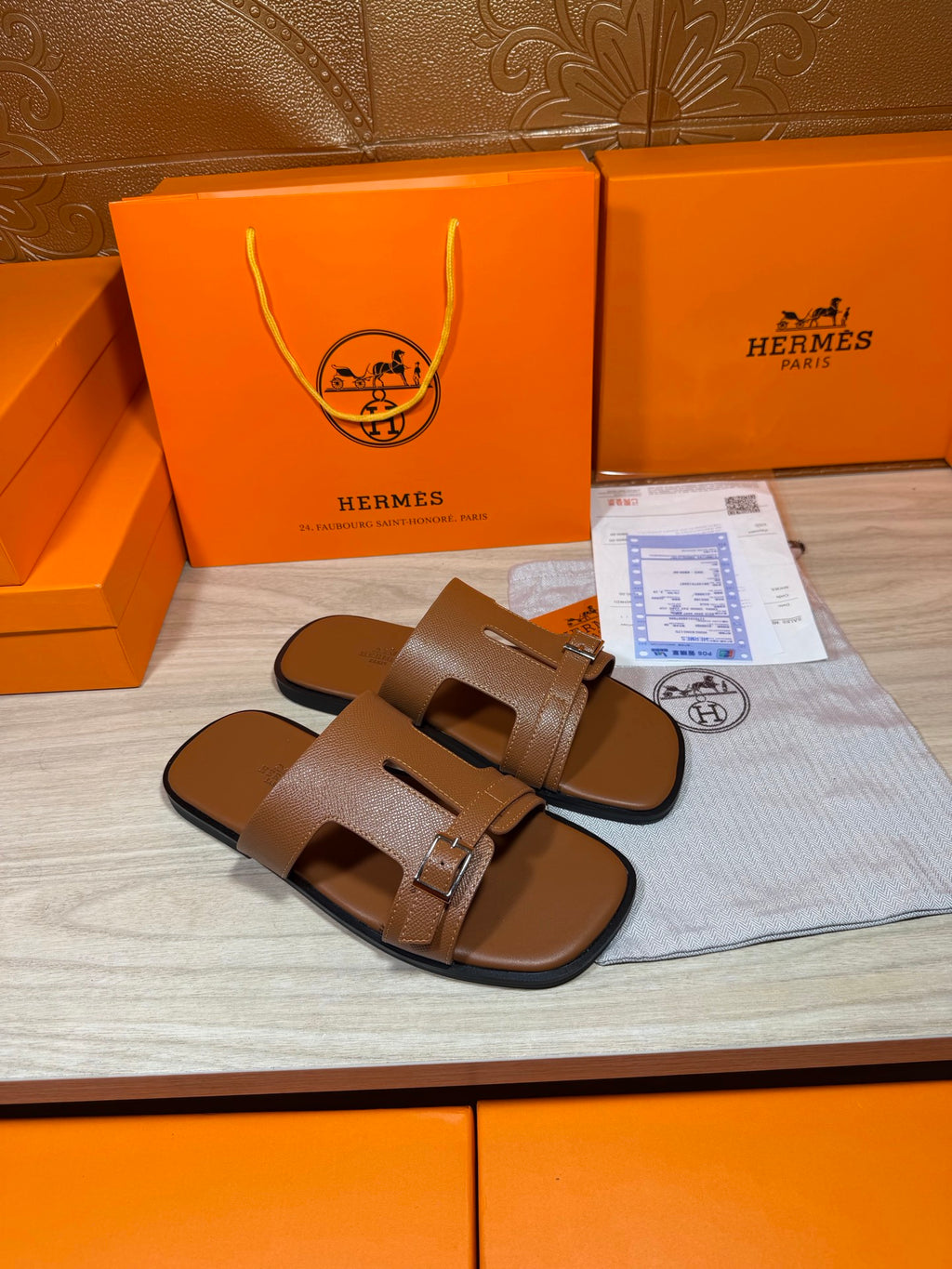 Hermes brown leather slide sandals with double strap and square metal buckle, angled