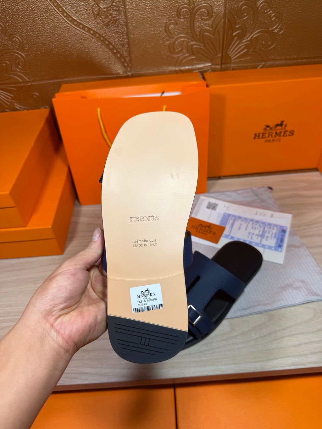 Navy slide sandal sole with embossed branding and textured tread, held up to camera