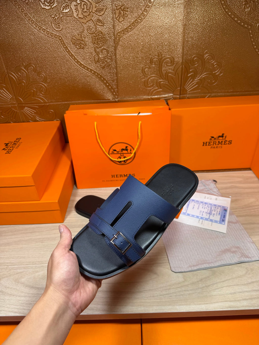 Navy two-strap sandal in hand, adjustable buckle strap detail visible from above