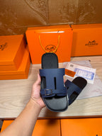 Navy slide sandals in hand, front strap and buckle hardware clearly visible