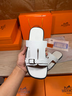 White leather slide sandal front view with two straps and metal buckle