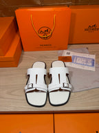 White leather slide sandals with black-trimmed edges and adjustable buckle straps