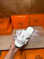 White leather slide sandals held together, showing twin buckled straps