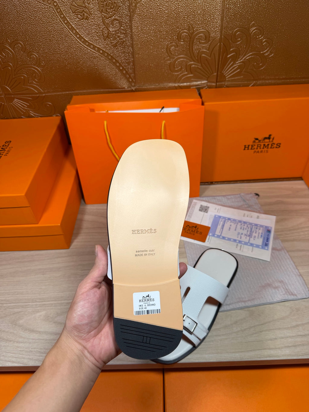 White sandal sole and underside held in hand, with label and strap opening