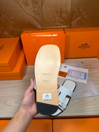 White sandal sole and underside held in hand, with label and strap opening