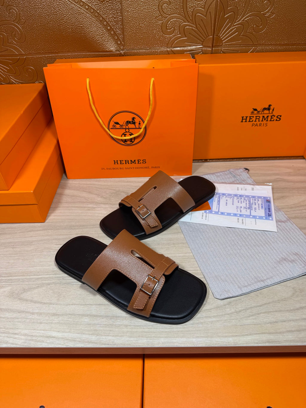Tan leather double-strap slide sandals with gold-tone buckles on black footbeds