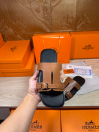 Tan leather slide sandals with two buckled straps and black footbed, front view