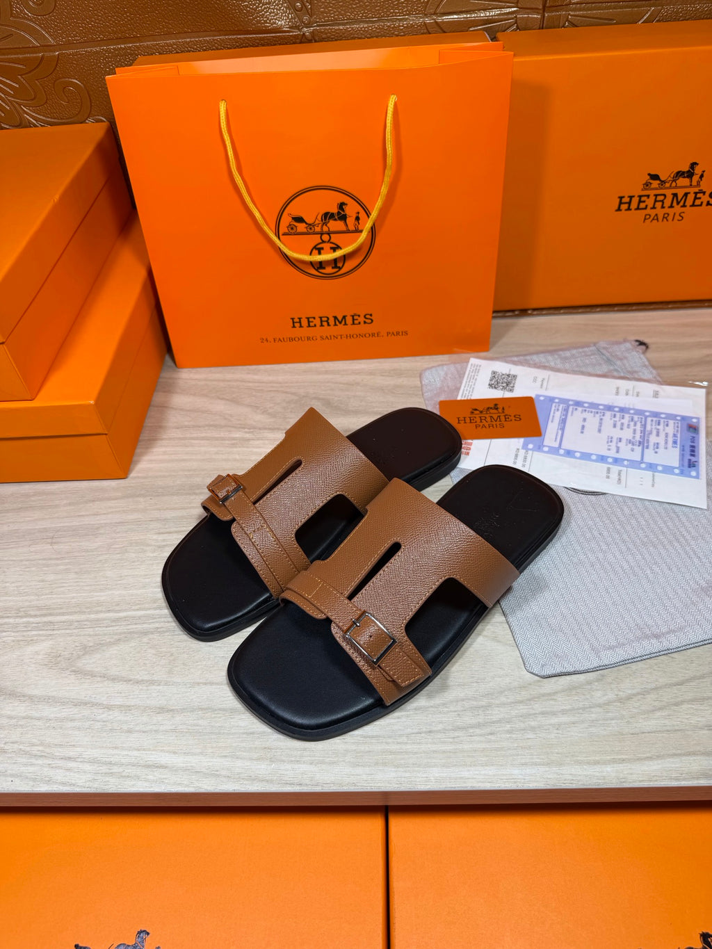 Tan leather slide sandals with gold-tone buckle strap and black footbed, double-strap