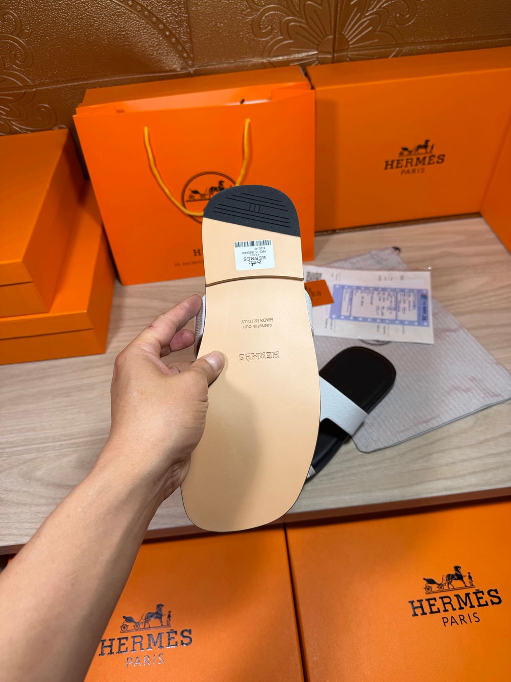 Black sandal sole with attached size label, held by hand