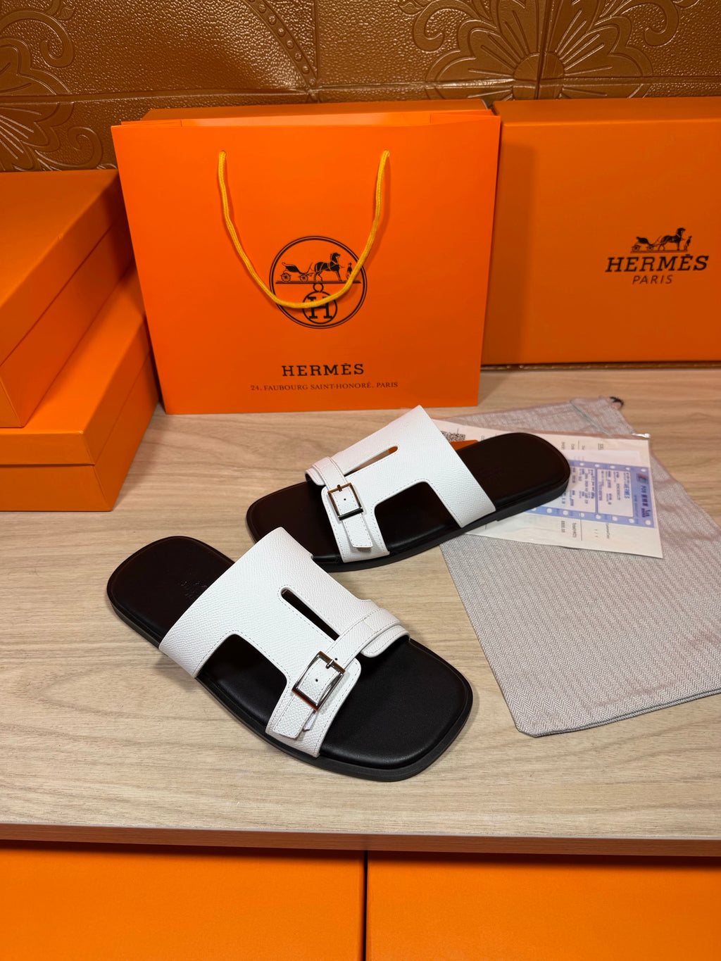 White slide sandals with rectangular buckles on black footbed