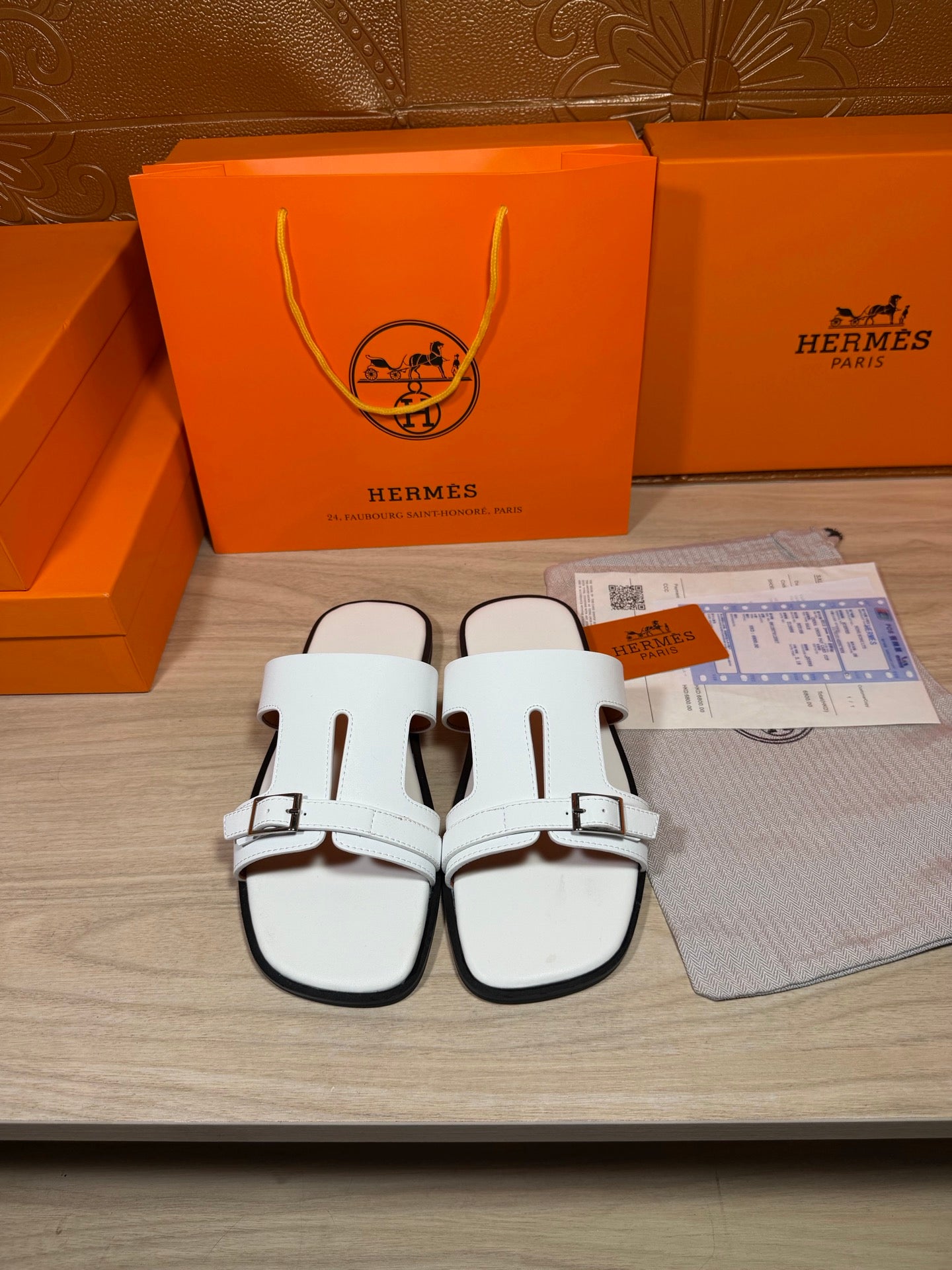 White slide sandals with two wide straps and silver-tone buckles