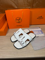 White slide sandals with front cutout straps and adjustable buckle closures