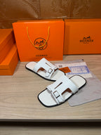Pair of white slide sandals with two wide straps and silver-tone buckles