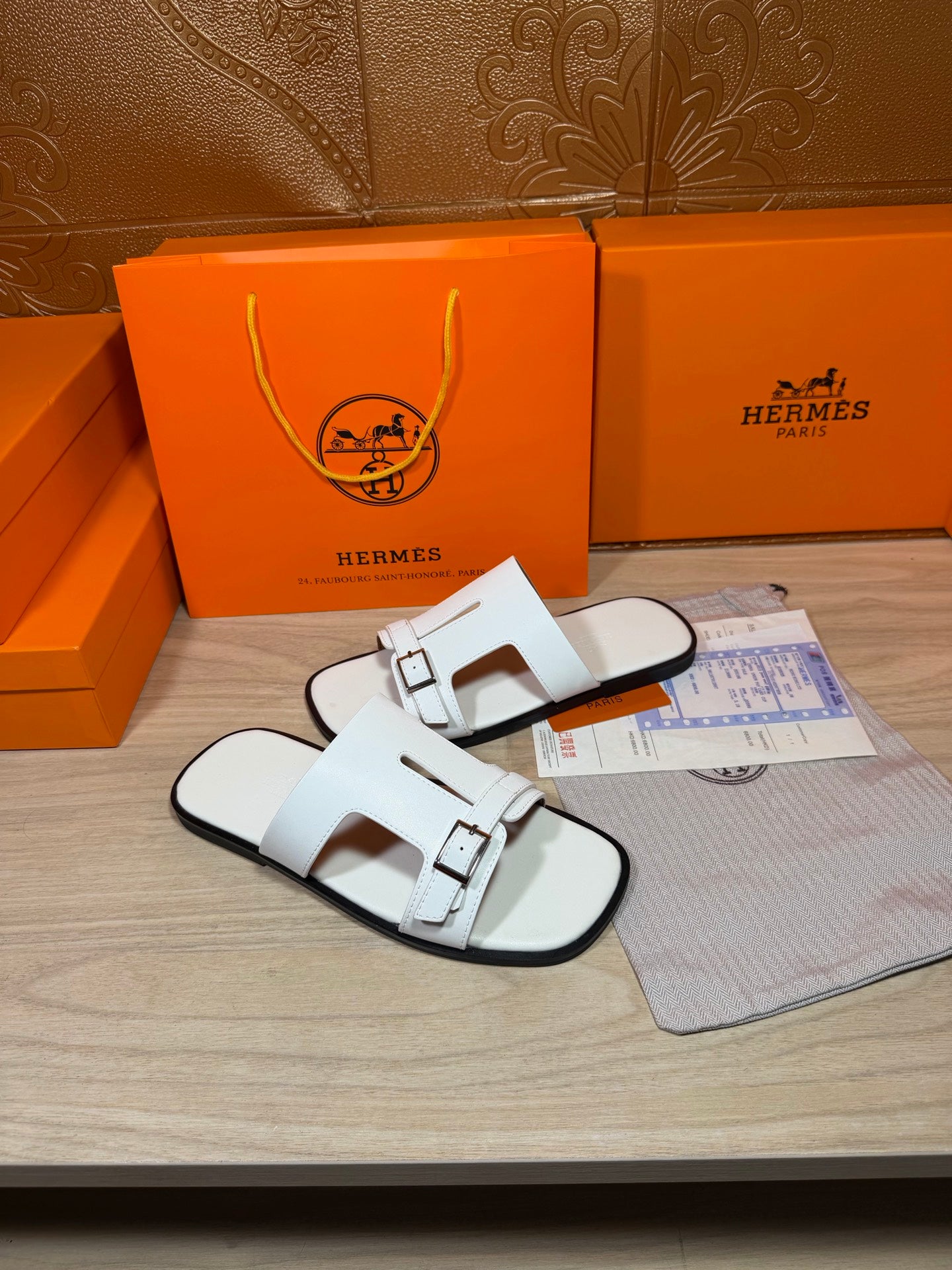 White slide sandals with double straps and metal buckle at top strap