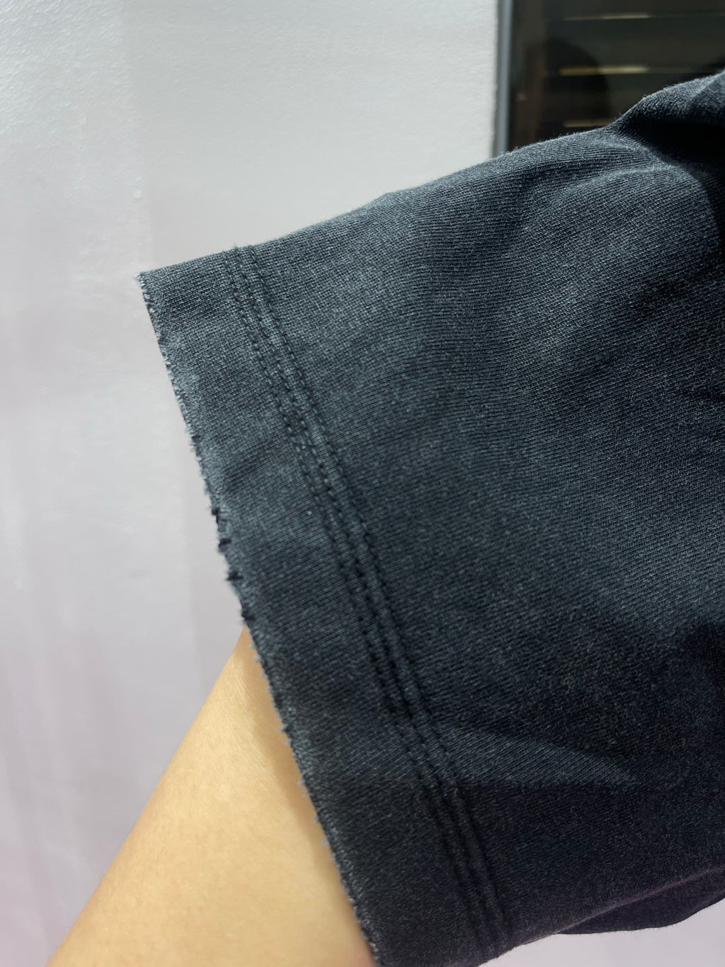 Dark charcoal T-shirt sleeve cuff with visible stitched hem