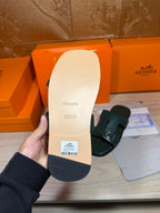 Hermes teal-green slide sandal outsole view with dark tread and stamped logo