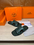 Hermes teal-green slide sandals with two buckled straps and molded footbed