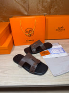 Brown leather slide sandals with double straps and metal buckle detail