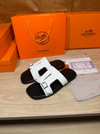 White Hermes slide sandals with square buckle straps and black footbeds