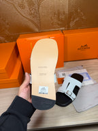 Sandal sole underside held by hand, white leather upper and dark rubber tread