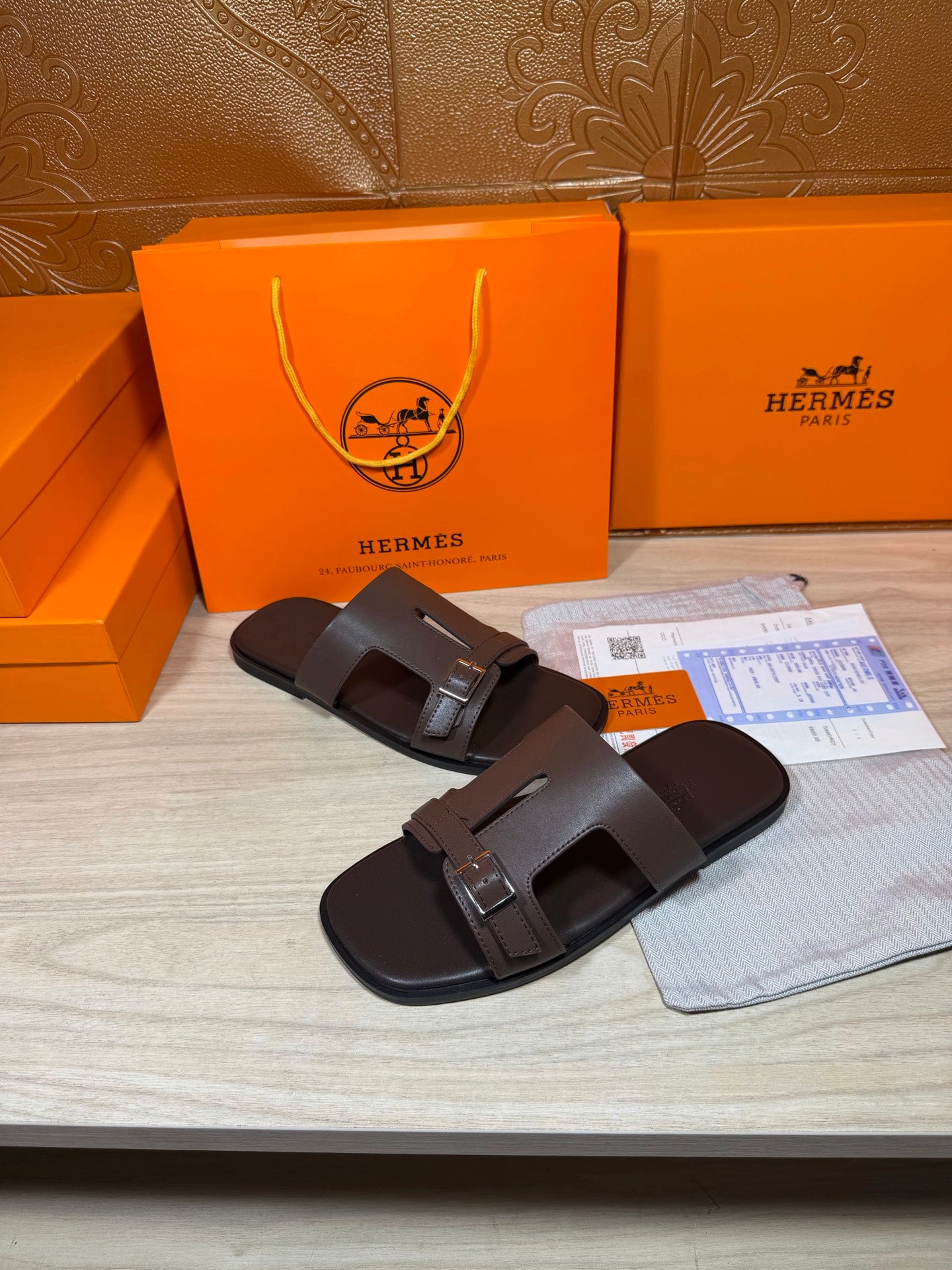 Brown leather slide sandals with two buckled straps, angled view