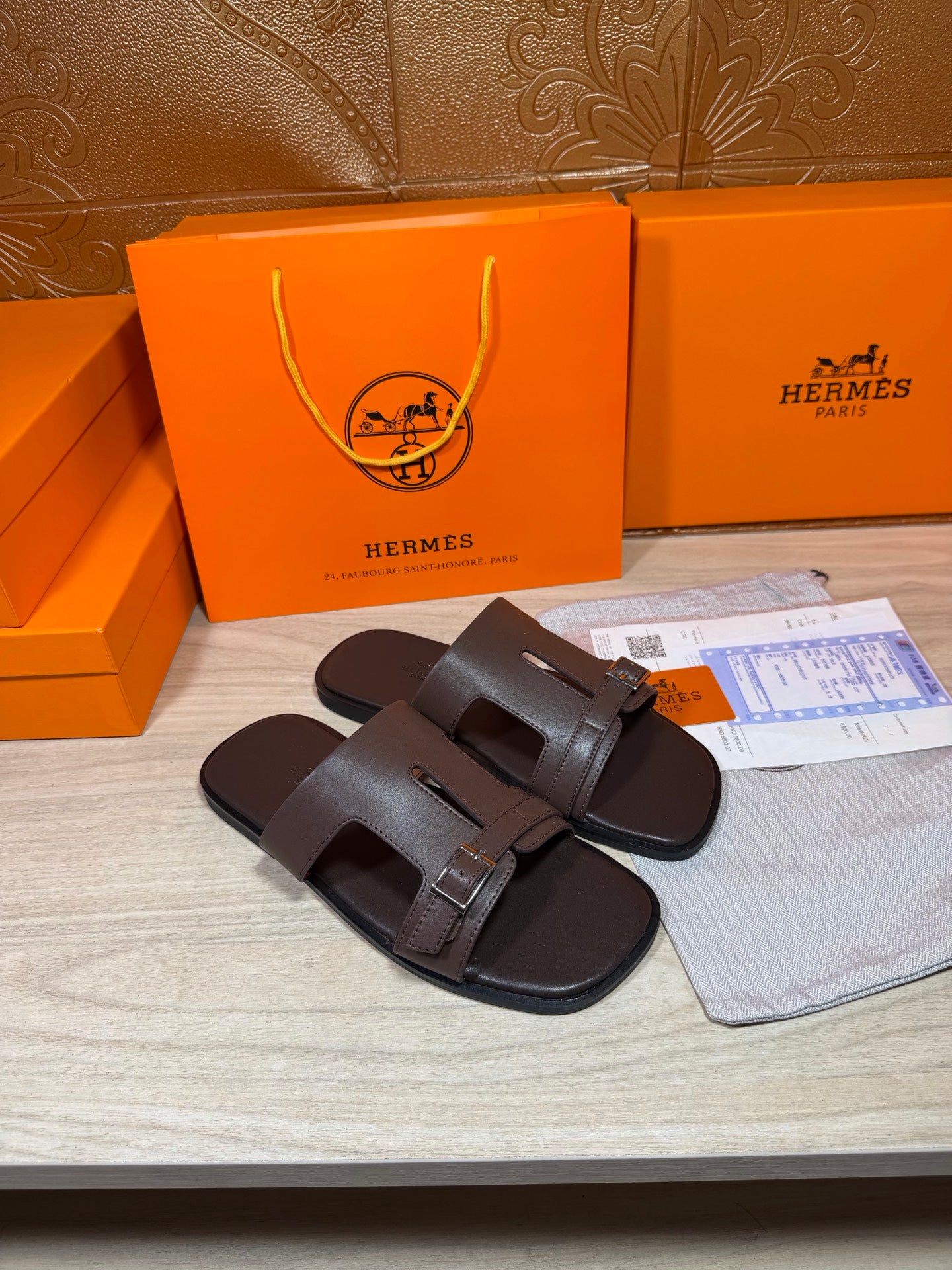 Brown leather slide sandals with two buckled straps on a flat surface