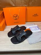 Black slide sandals with adjustable buckle straps, shown from side angle