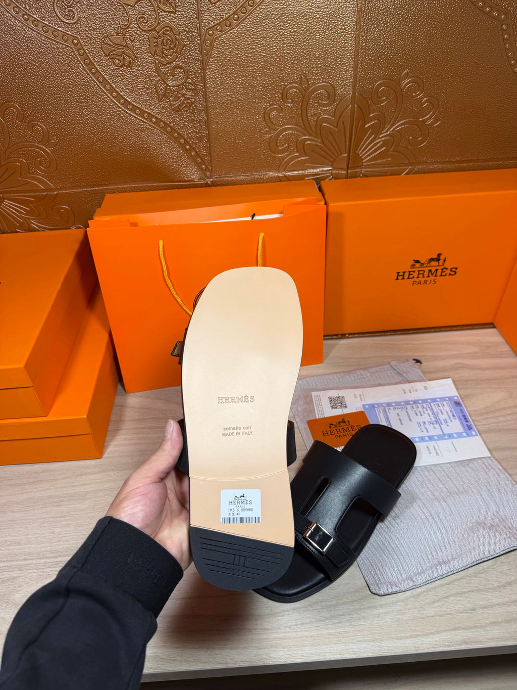Black sandal sole and footbed shown in hand, with side strap visible