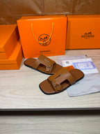 Hermes tan leather slide sandals with double straps and square buckle, profile view.