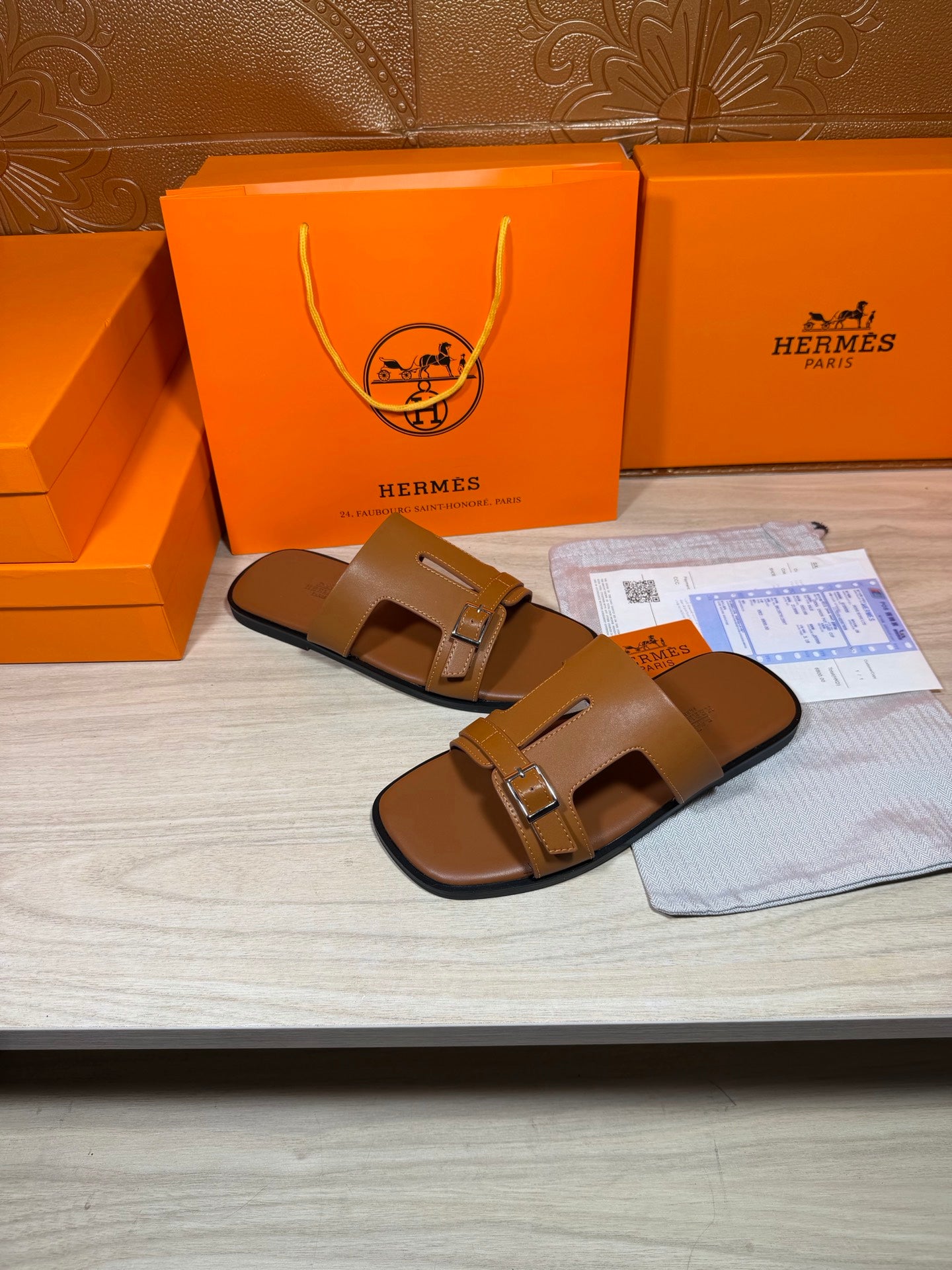 Hermes tan leather slide sandals with double straps and square buckle, profile view.