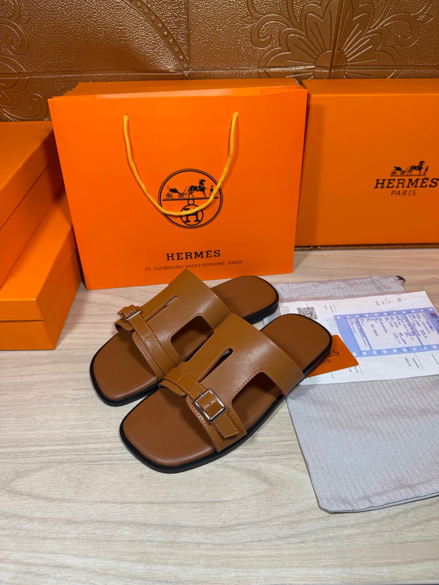 Hermes tan leather sandals, front view, two adjustable straps with square metal buckle.