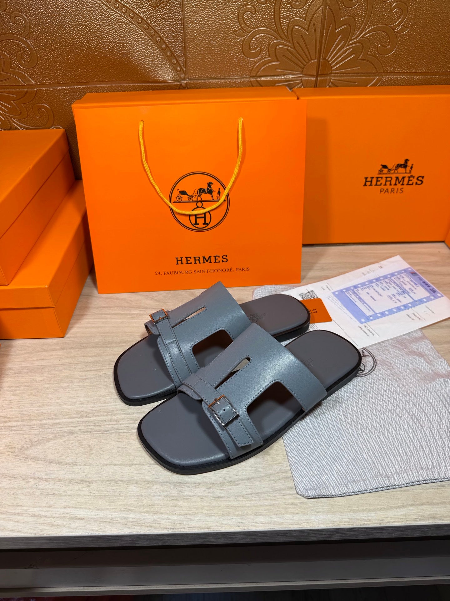 Hermes slide sandals showing two-tone footbed with light blue-gray strap and buckle.