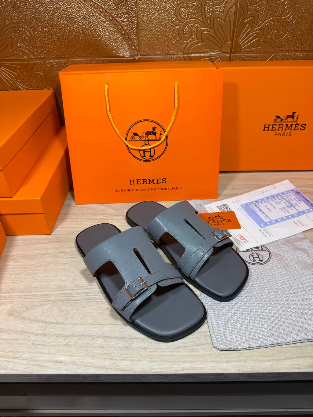 Hermes slide sandals in light blue-gray leather with wide front strap and buckle.