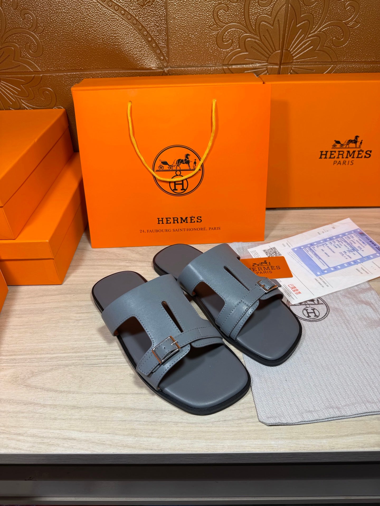 Hermes slide sandals in light blue-gray leather with wide front strap and buckle.