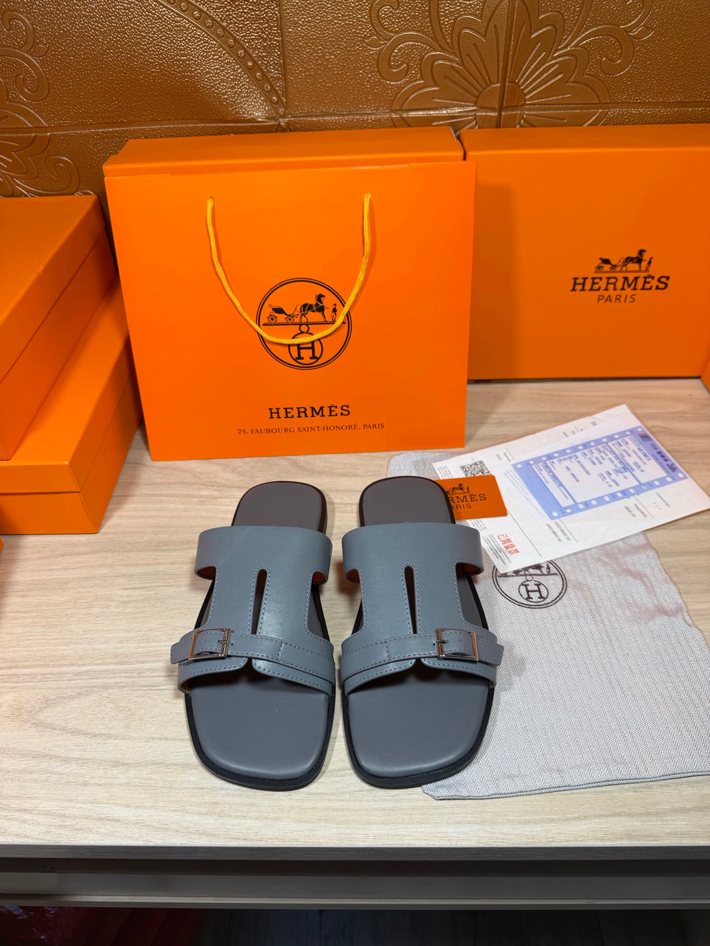 Hermes slide sandals with light blue-gray leather straps and adjustable buckle.