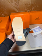 Hermes sandals heel view: light footbed with branding and textured sole underside.