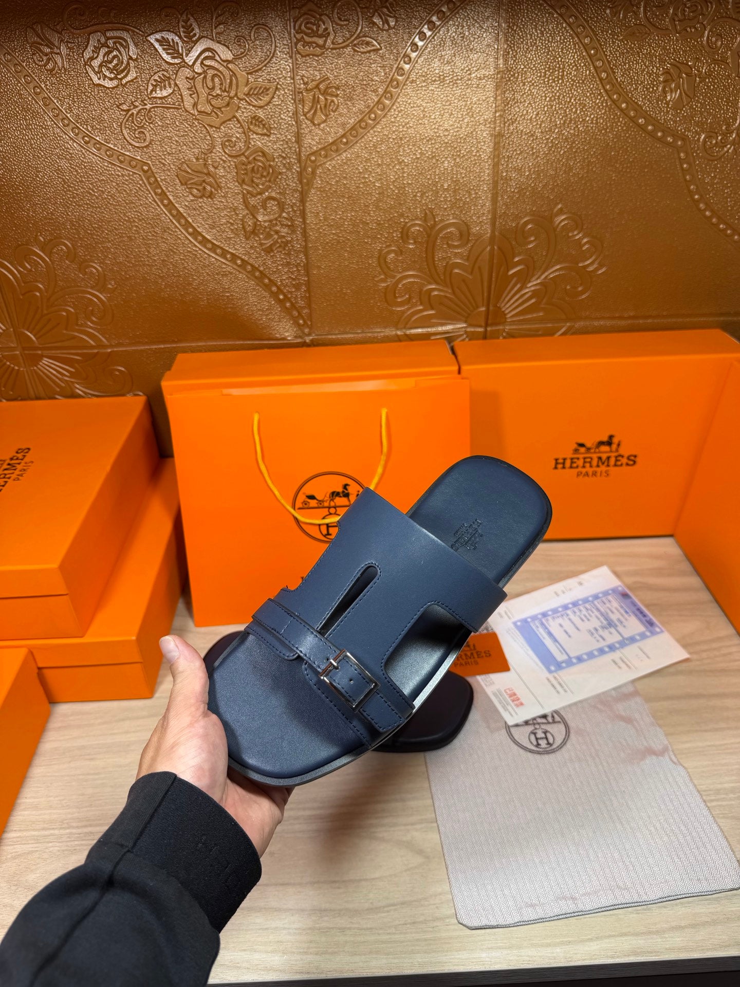Hermes blue slide sandal held up, single front strap with silver buckle