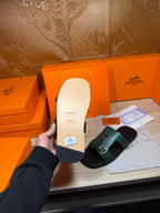 Hermes sandal sole detail with teal strap; black outsole and footbed shown