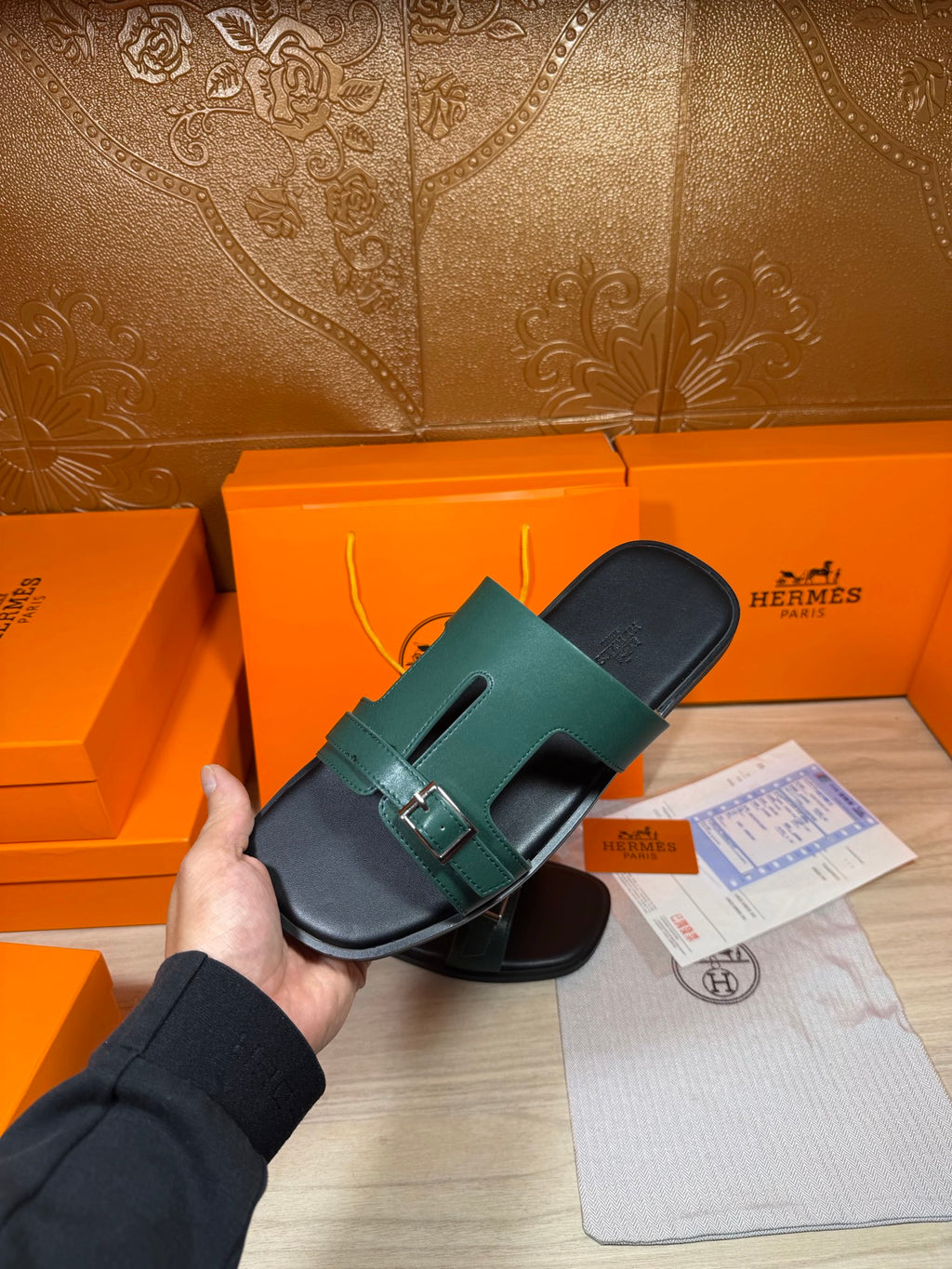 Hermes sandals held in hand: teal slide strap with silver buckle on dark footbed