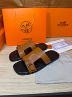 Tan and black leather slide sandals with wide front strap and buckle