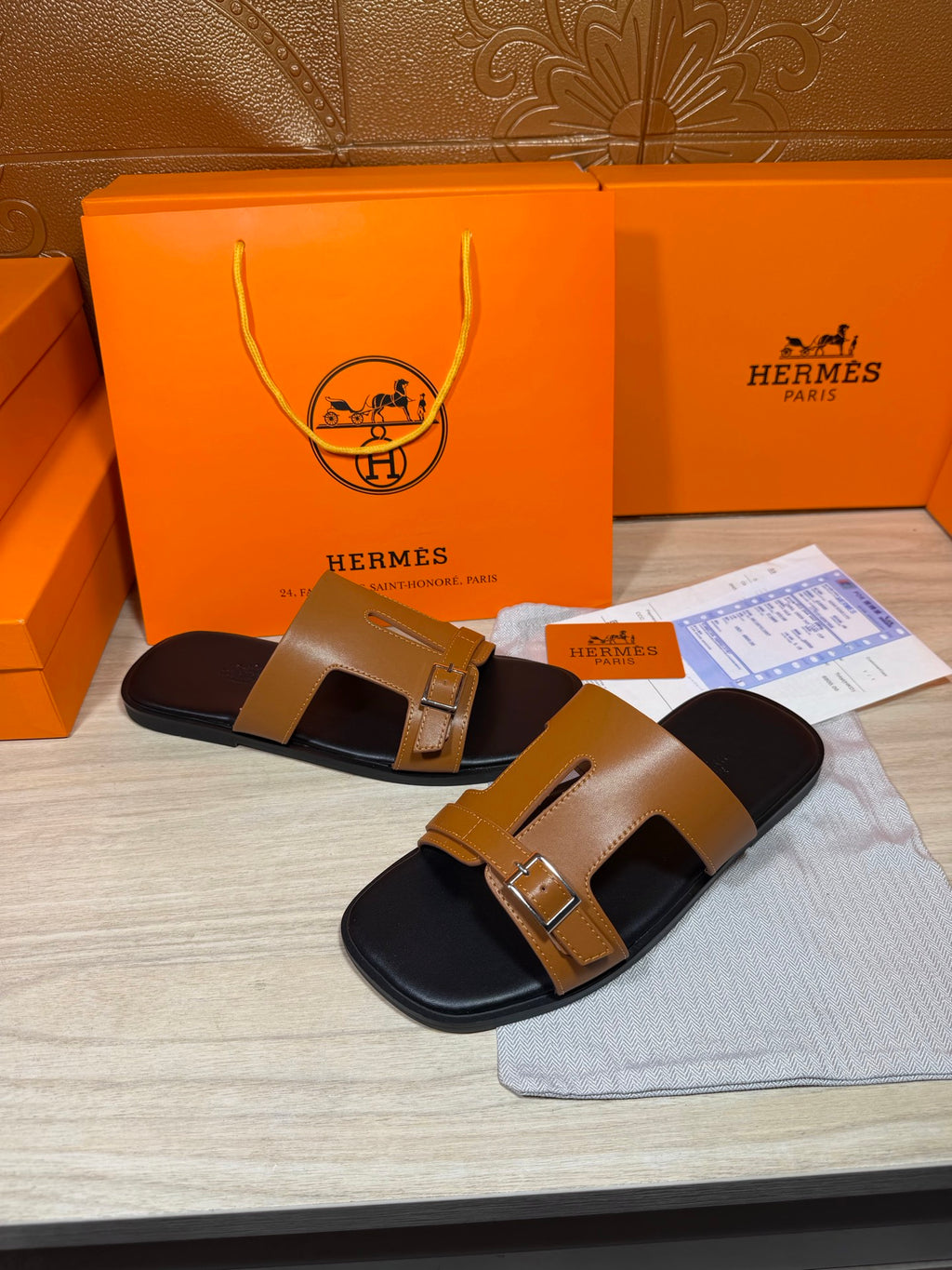 Tan and black leather slide sandals with wide strap and metal buckles