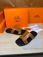 Tan and black leather slide sandals with wide strap and metal buckles