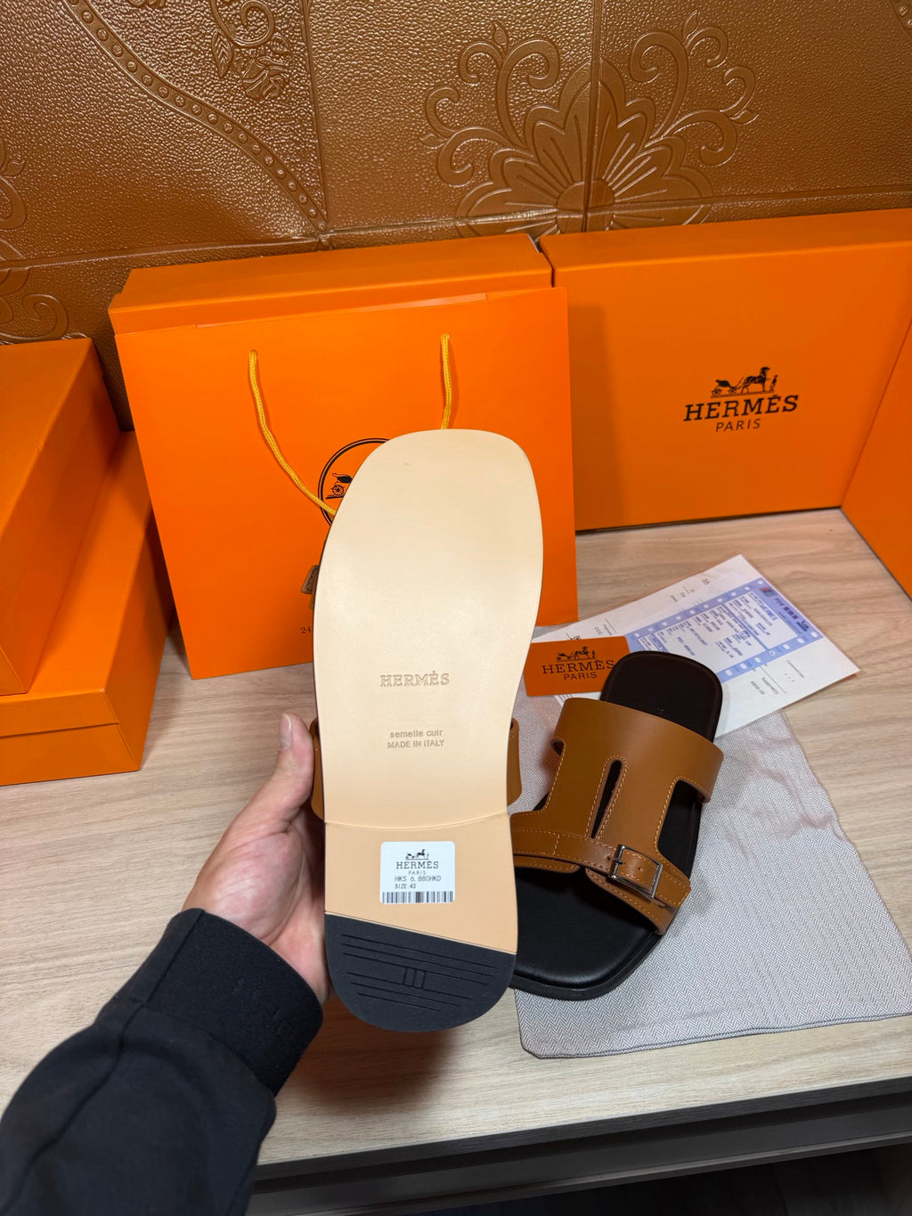 Sandal outsole view: white sole with tan strap and buckle detail