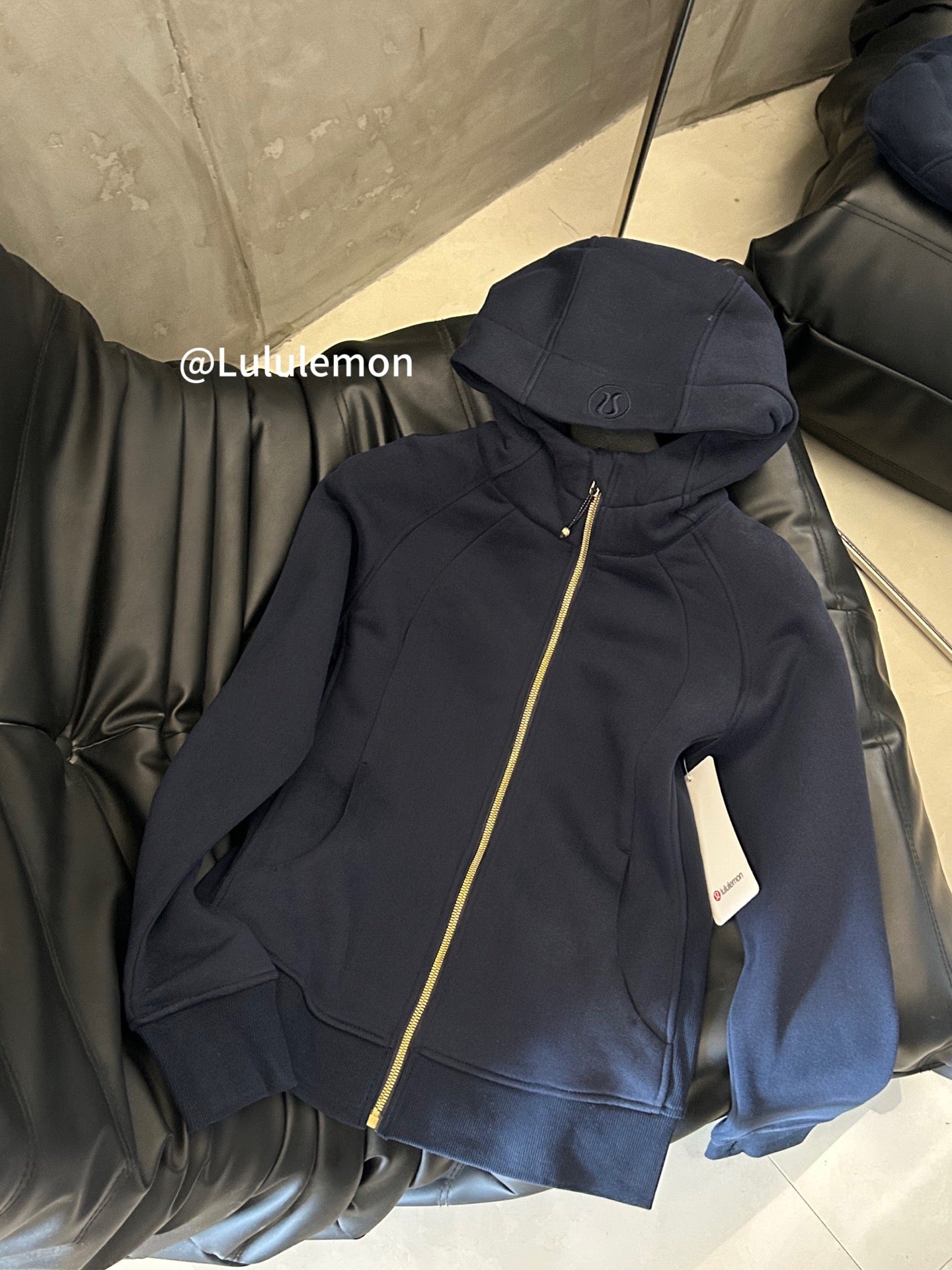 Navy zip-up hoodie with hood and gold-trim zipper, folded side view