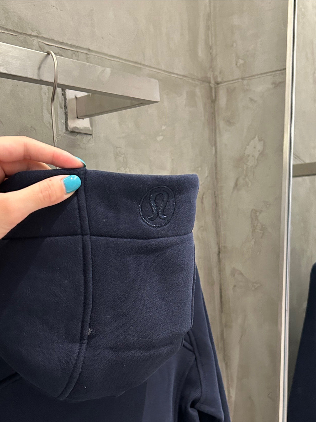 Navy hoodie hood with small logo emblem and stitched pocket front