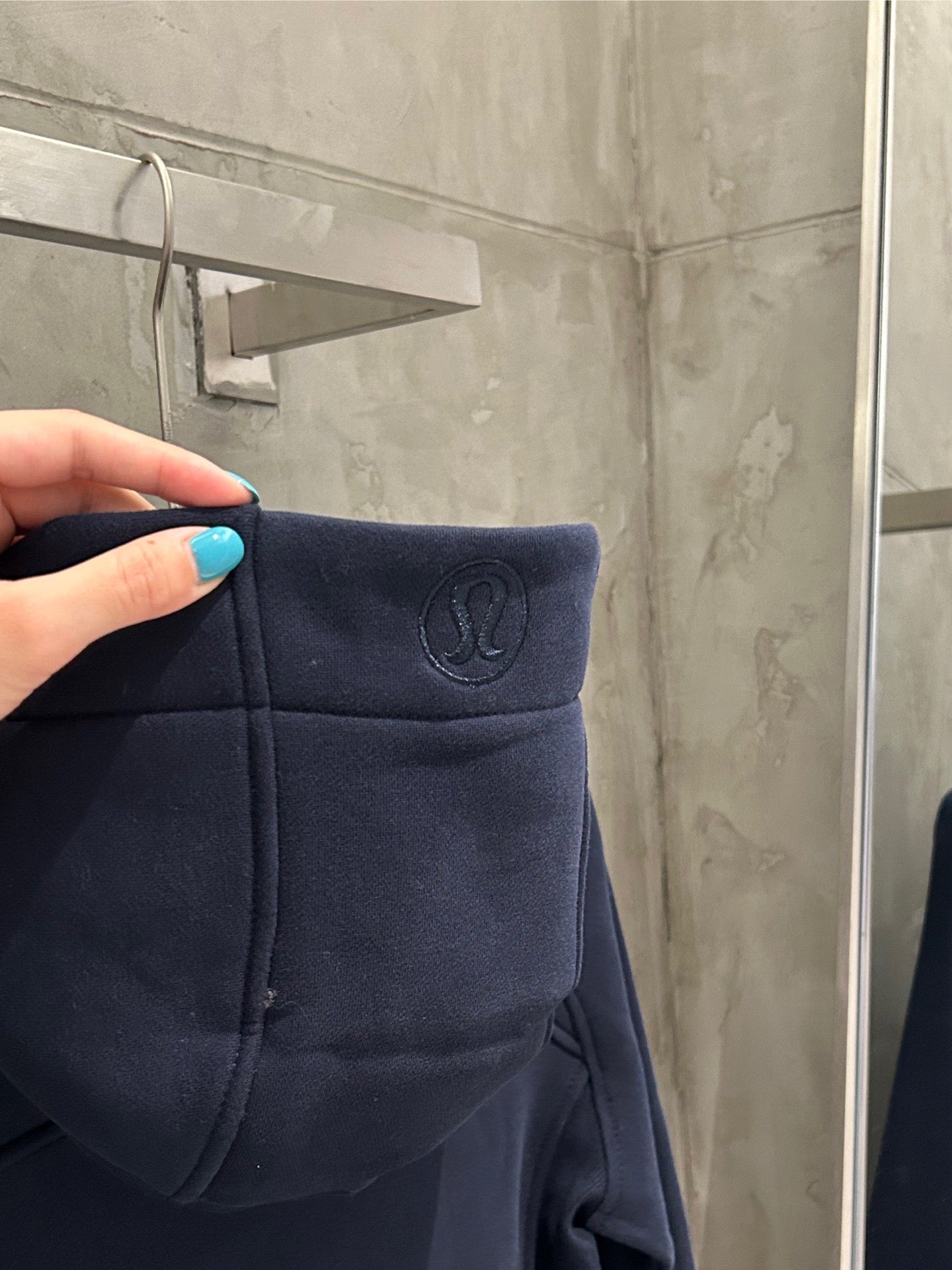 Navy hoodie hood with small logo emblem and stitched pocket front