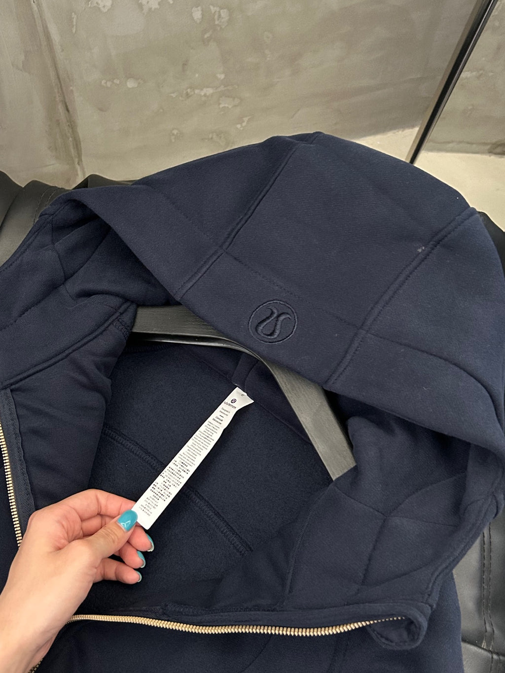 Navy hoodie front zipper and hood seam with white garment label tag