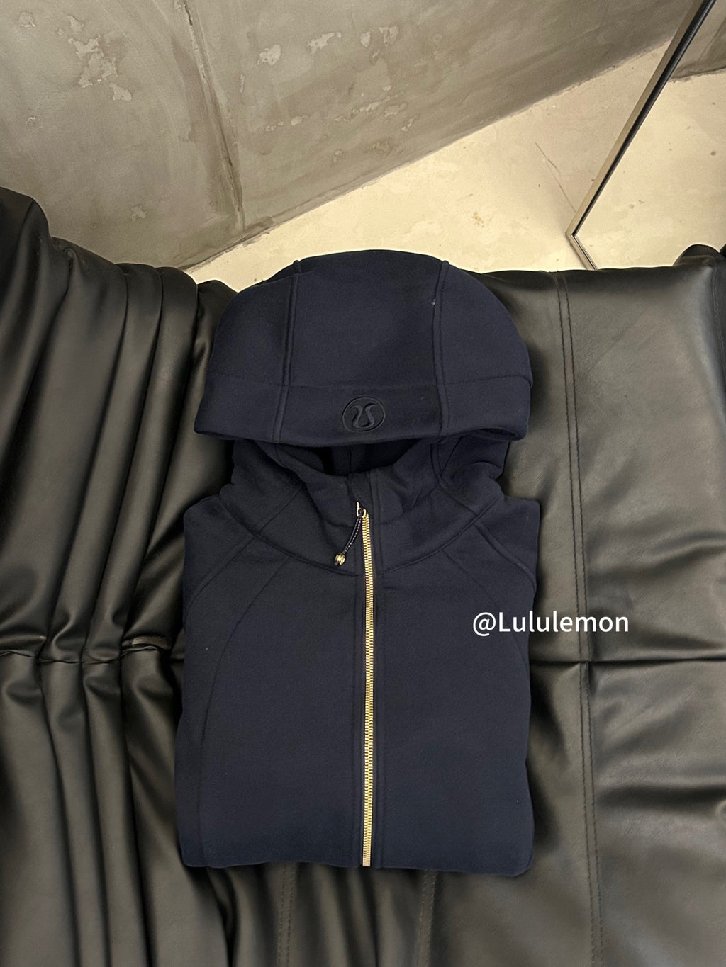 Navy zip-up hoodie with hood, small chest logo, and gold zipper trim